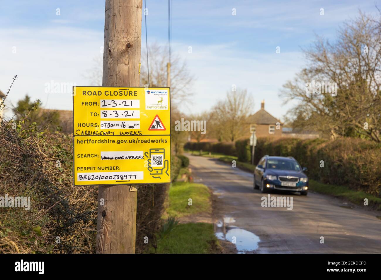 Panneau d'avis de fermeture de route dans une route de campagne avec un véhicule approchant dans un arrière-plan défocaalisé. Beaucoup Hadham, Hertfordshire. ROYAUME-UNI Banque D'Images