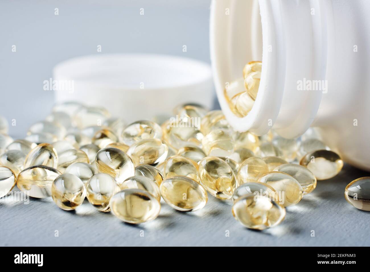 Capsules jaunes de vitamine D sur une surface grise. Banque D'Images