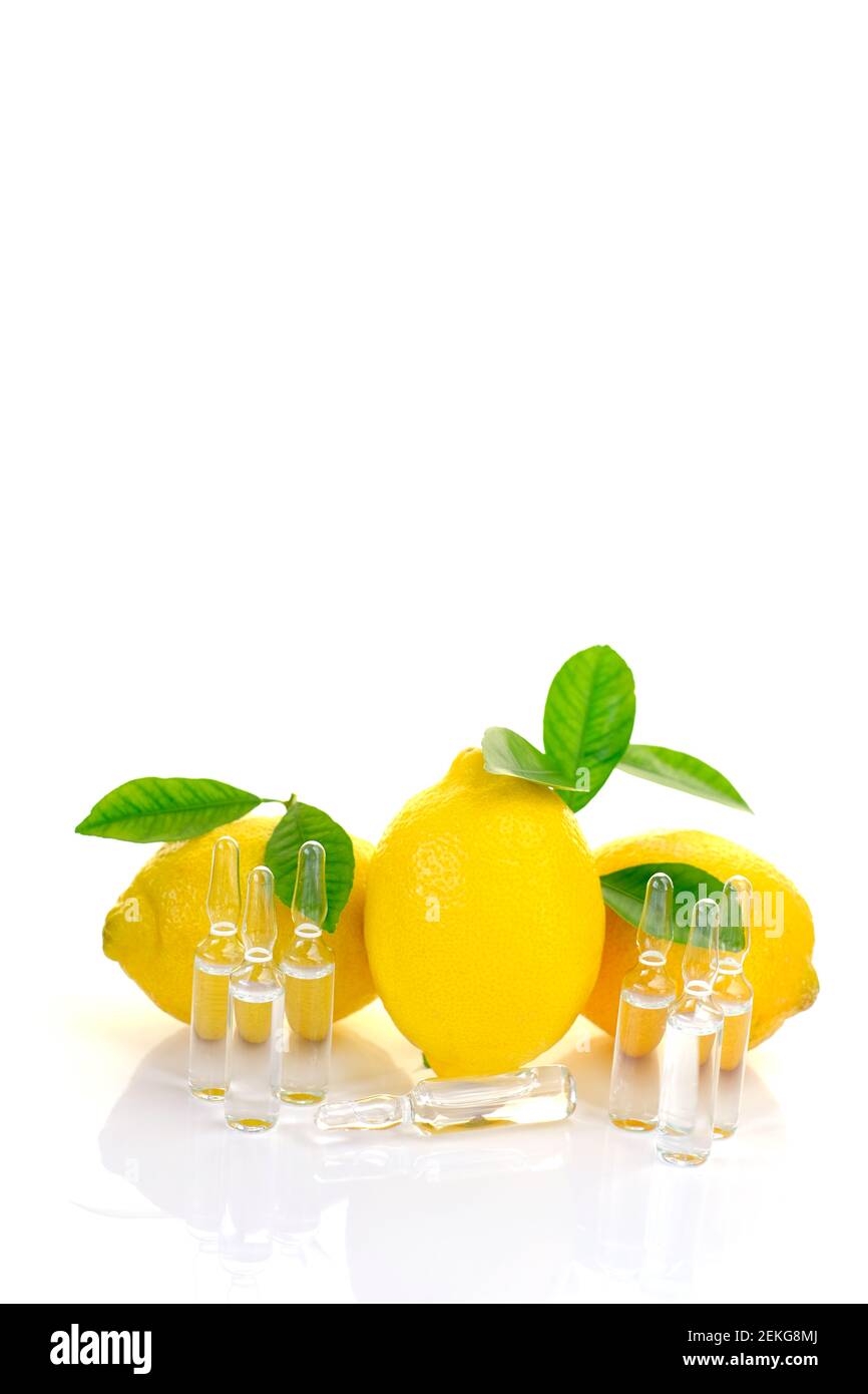 Vitamine C. prévention de l'immunité contre les virus.sérum avec vitamine C. ampoules transparentes, citrons fruits avec feuilles vertes sur fond blanc avec Banque D'Images