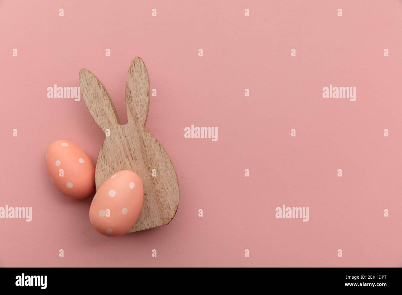 Arrière-plan minimal pour les vacances de pâques. Lapin de pâques en bois et œuf sur rose Banque D'Images