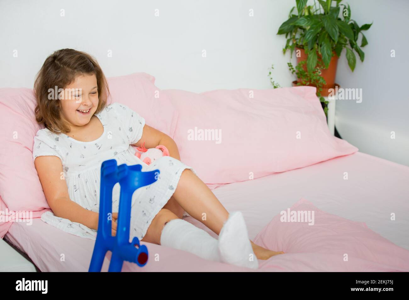 Une adolescente joyeuse se trouve sur le lit après avoir fait jeter sa jambe dans la salle d'urgence. L'enfant a une jambe cassée, un os cassé Banque D'Images