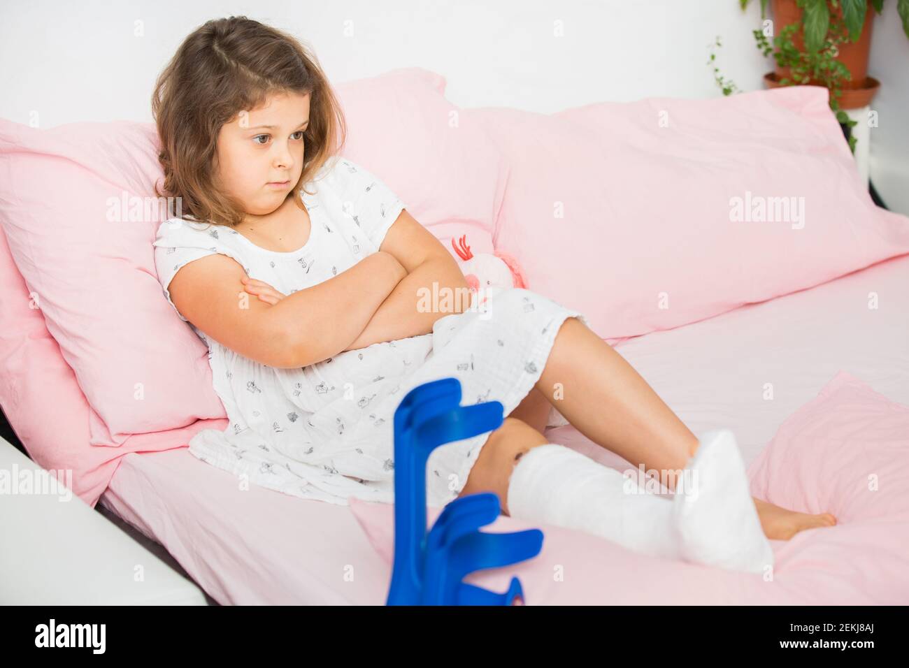 Une jeune fille triste se trouve sur son lit après une coulée dans la salle d'urgence. L'enfant a une jambe cassée, un os cassé Banque D'Images