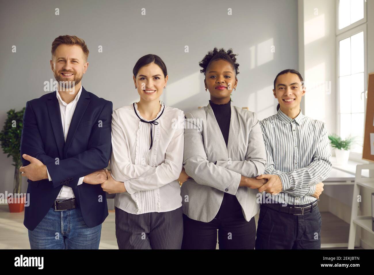 Équipe de gens heureux qui travaillent dans une entreprise en tenant les mains, souriant et regardant la caméra Banque D'Images