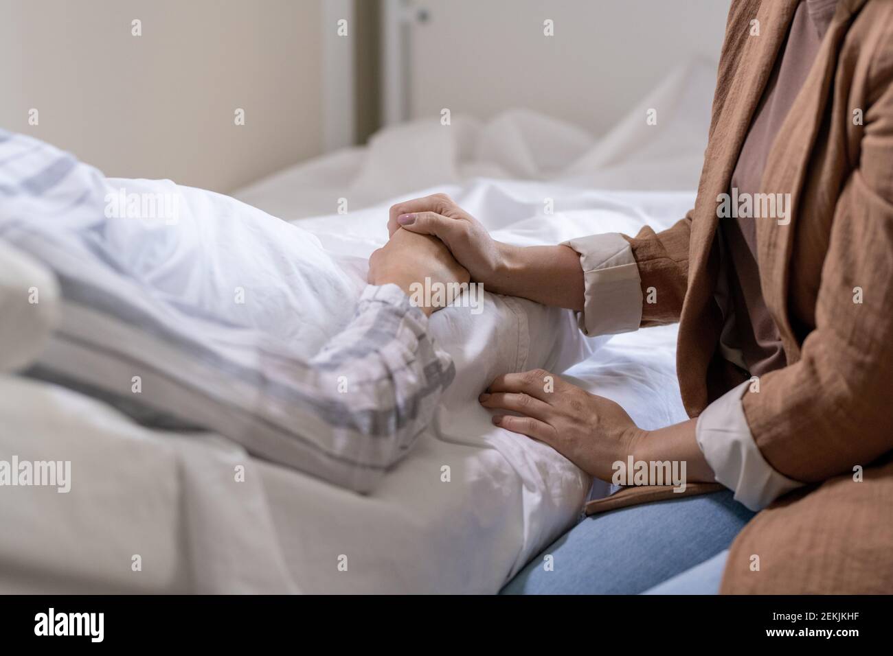 Main de la jeune femme emphatique en tenue décontractée tenue de celle de  son amie malade en pyjama couché dans le lit dans moderne chambre d'hôpital  Photo Stock - Alamy