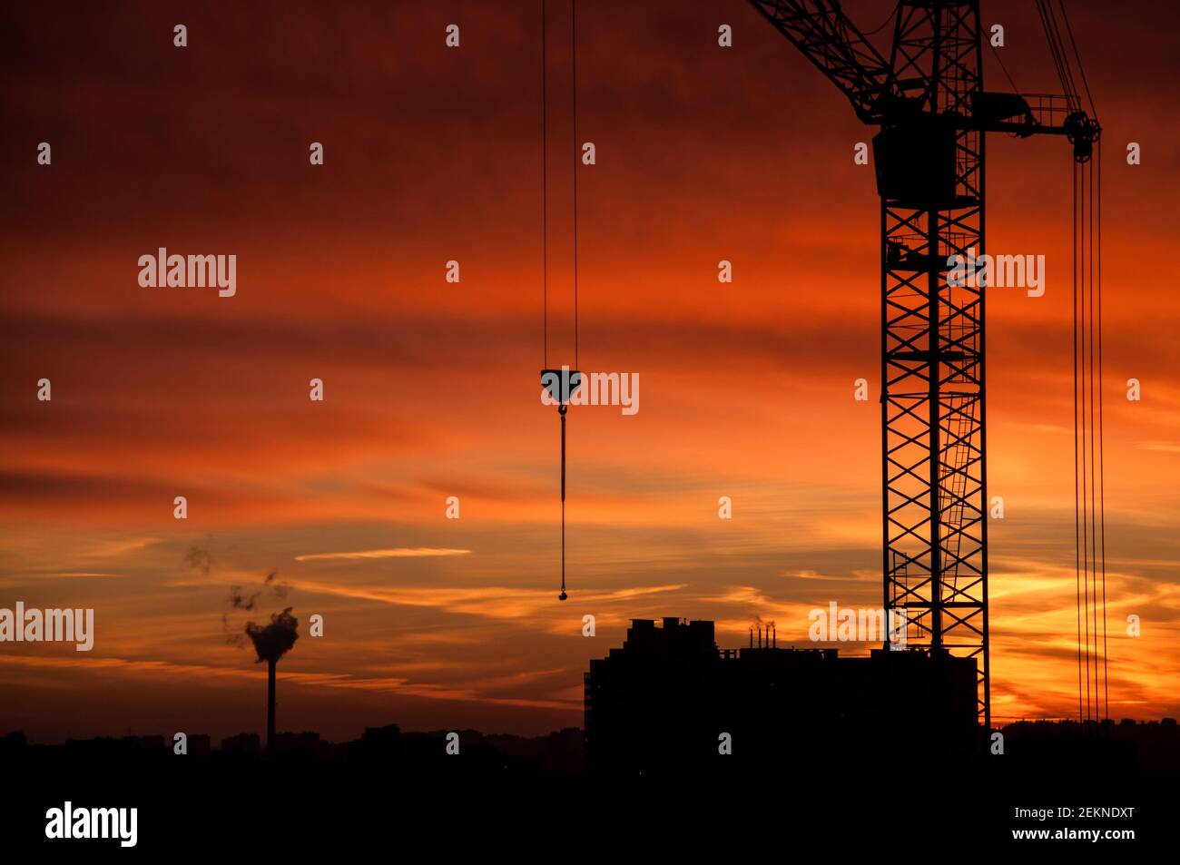Silhouette de la grue de construction industrielle contre le ciel orangé du coucher du soleil Banque D'Images
