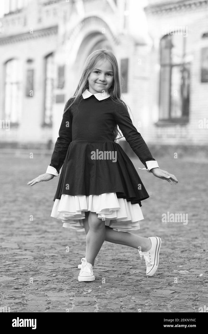 Étiquette de danse. Un enfant heureux fait des petites fleurs dehors. Petite danseuse portant un uniforme scolaire. Retour à la mode scolaire. Éducation à la danse. Laissez vos pieds parler. Banque D'Images