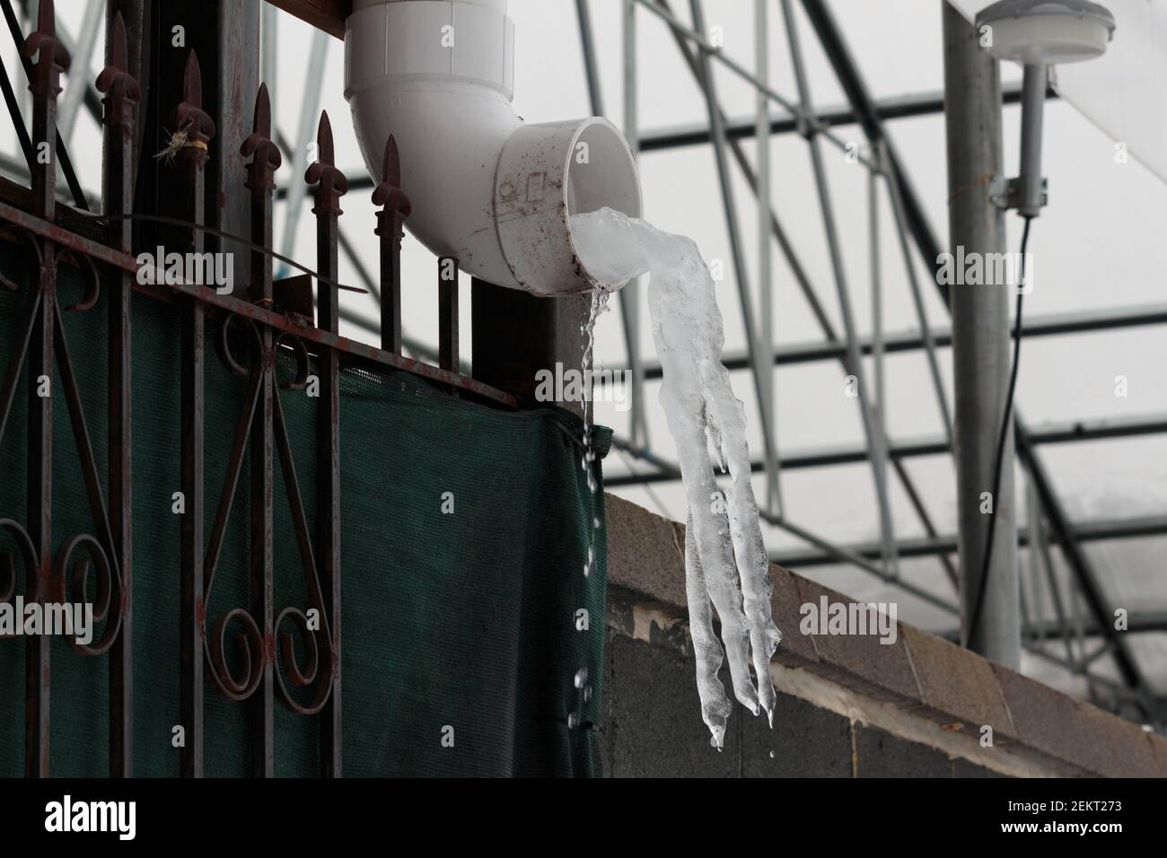 les glaçons se forment à partir de l'eau qui sort d'une gouttière, l'eau gelée à mi-air, de l'eau liquide coule en dessous Banque D'Images