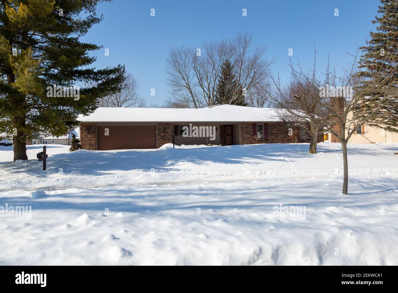 Une couverture de neige couvre cette maison de style ranch lors d'une journée d'hiver ensoleillée à Auburn, Indiana, États-Unis Banque D'Images