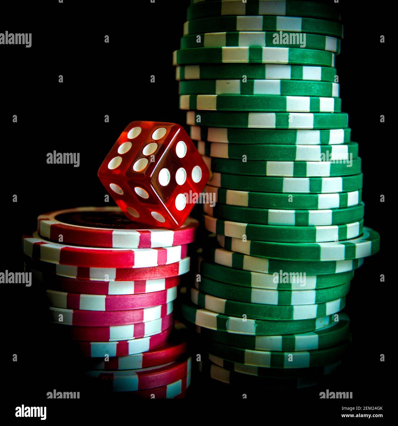 Les dés rouges reposent sur des jetons de poker verts et rouges dans un cadre sombre, soulignant l'essence du jeu et du hasard Banque D'Images