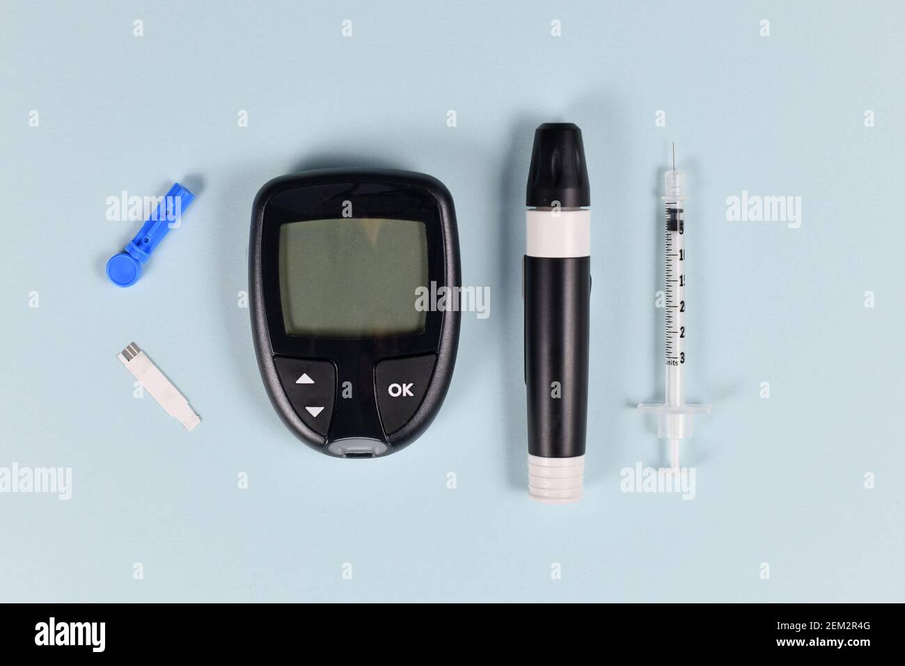 Équipement de traitement du diabète avec glucomètre, lancet, seringue et dispositif de lancing sur fond bleu Banque D'Images