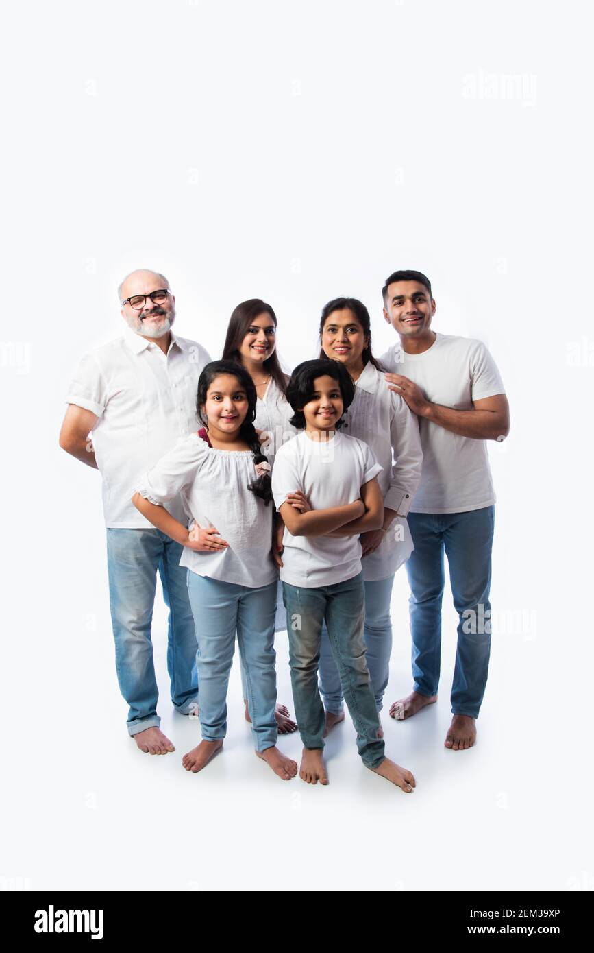 Famille indienne multigénérationnelle dans des tissus blancs debout et regardant caméra sur fond blanc Banque D'Images