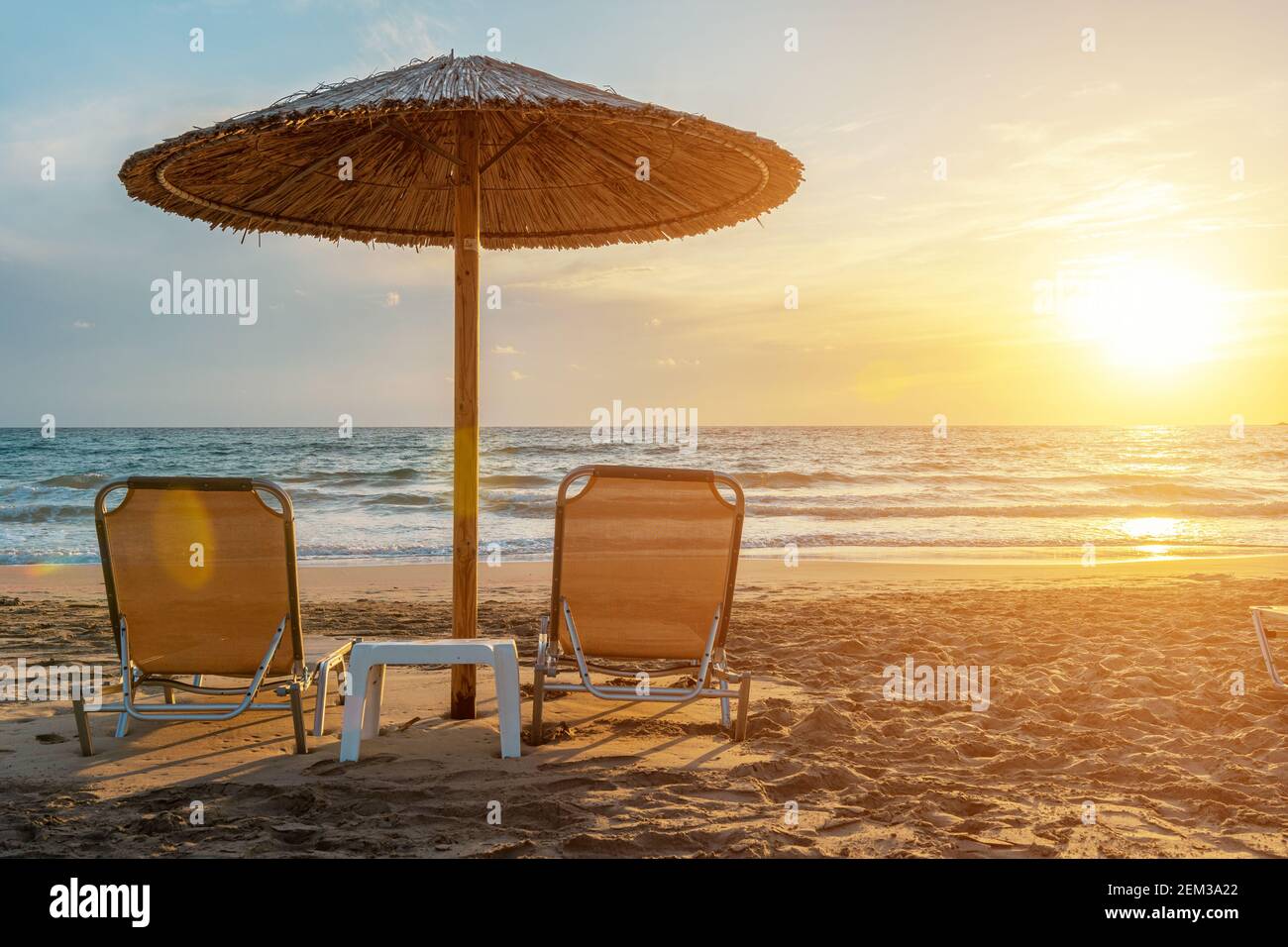 Deux chaises sous un parasol sur la plage tropicale au coucher du soleil. Concept de vacances d'été. Banque D'Images