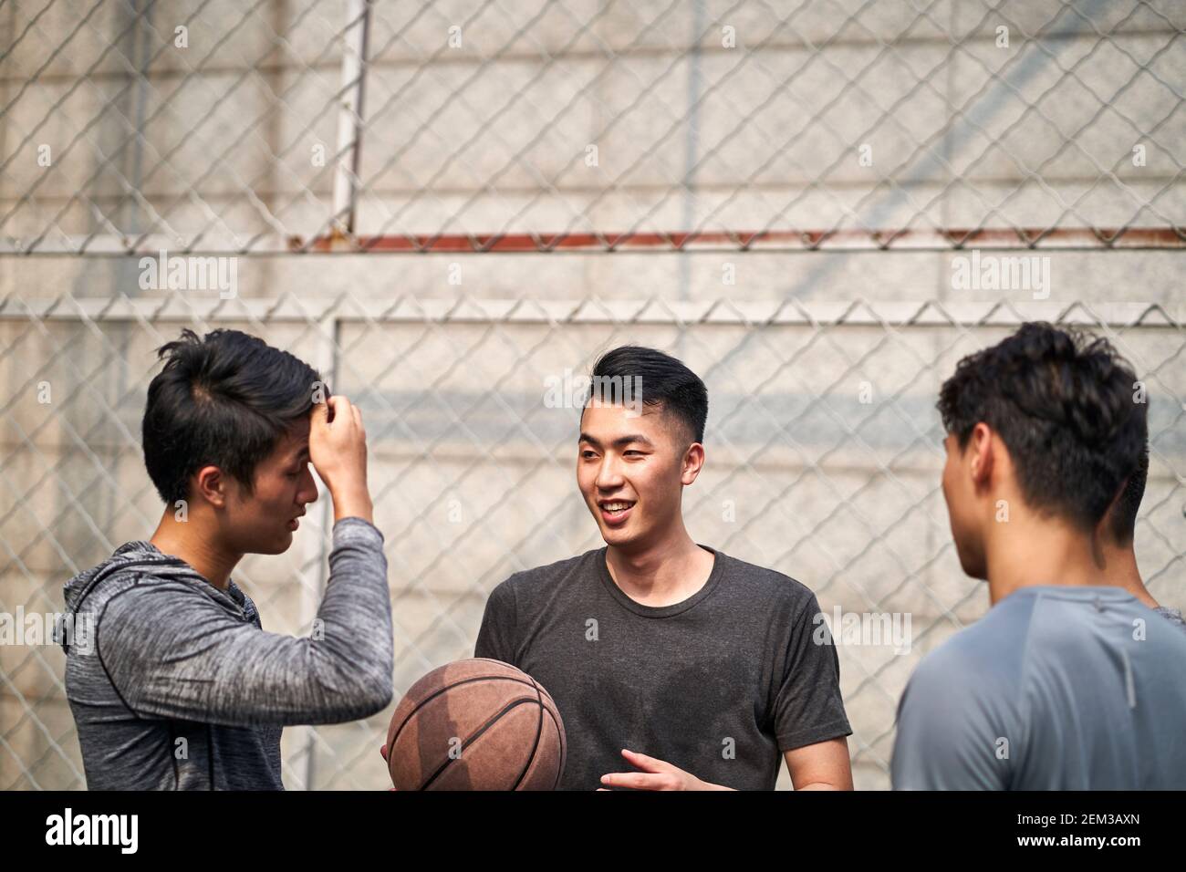 de jeunes joueurs de basket-ball asiatiques bavardent en parlant en se relaxant sur un terrain en plein air Banque D'Images