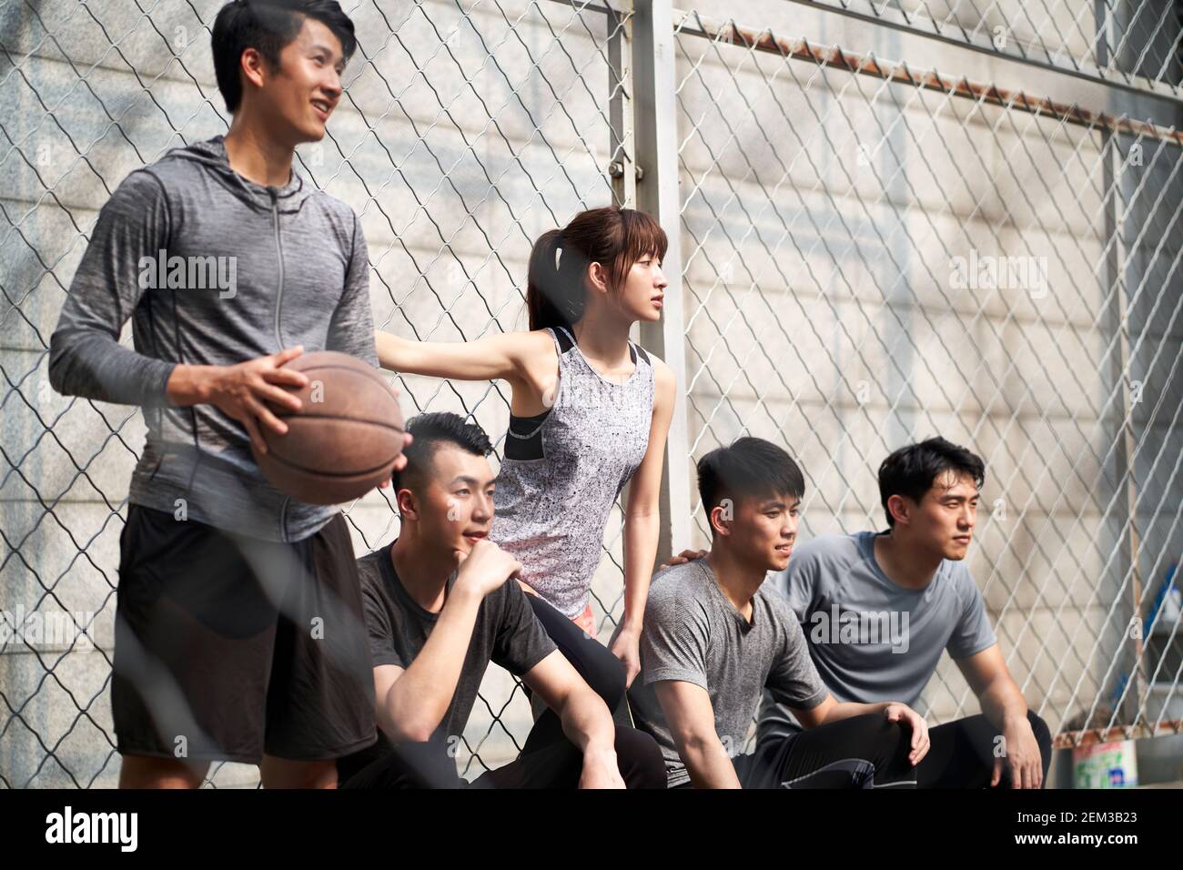 groupe de cinq jeunes adultes asiatiques, hommes et femmes, se reposant sur un terrain de basket-ball extérieur Banque D'Images