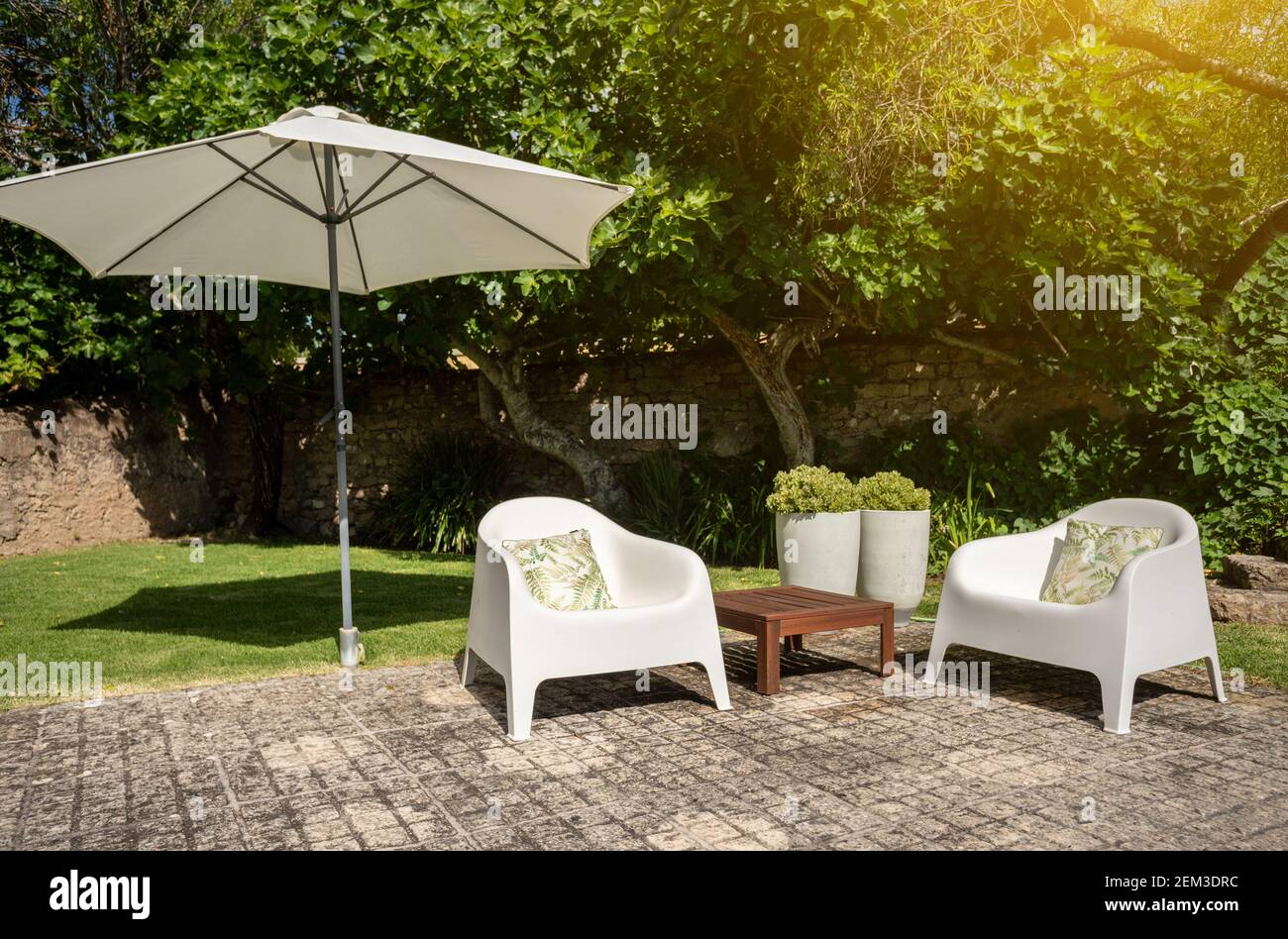 Jardin vert avec quelques chaises blanches, une petite table et un grand  parasol pour fournir l'ombre lors d'une journée ensoleillée Photo Stock -  Alamy