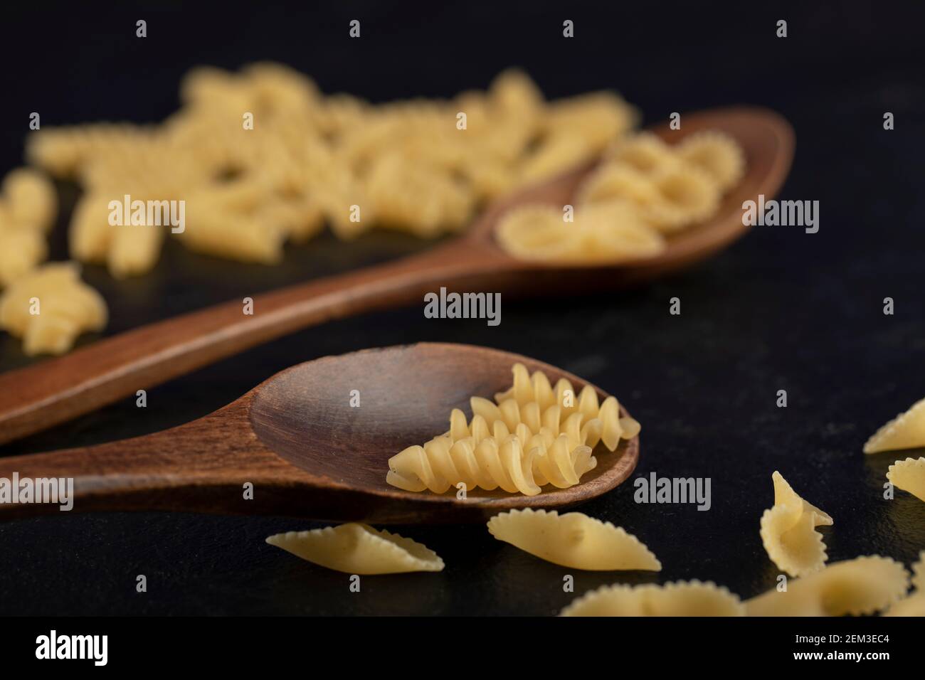 Une cuillère en bois remplie de pâtes de girandole crues Banque D'Images