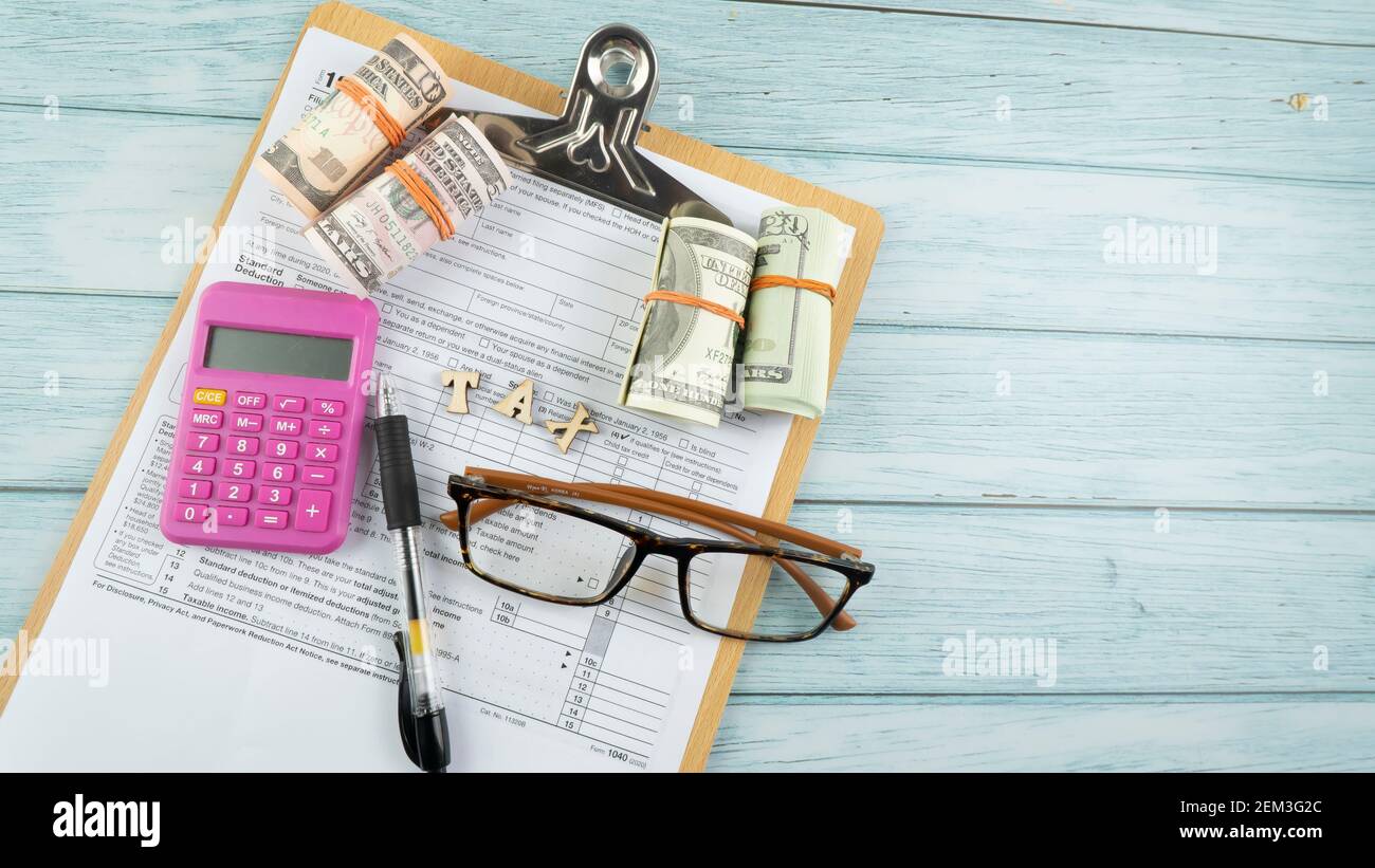 Concept de taxation - mots "Tax Time" sur fausse monnaie, stylo, lunettes représentant la moitié du formulaire US IRS 1040. Banque D'Images