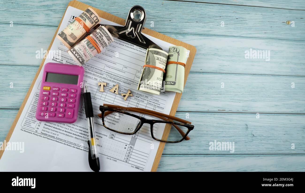 Concept de taxation - mots "Tax Time" sur fausse monnaie, stylo, lunettes représentant la moitié du formulaire US IRS 1040. Banque D'Images