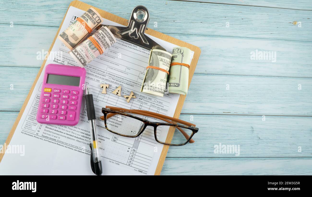 Concept de taxation - mots "Tax Time" sur fausse monnaie, stylo, lunettes représentant la moitié du formulaire US IRS 1040. Banque D'Images