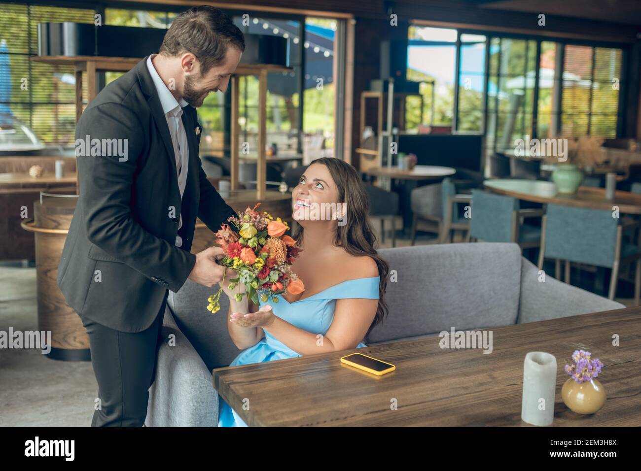 Homme souriant avec des fleurs touchant l'épaule de la femme Banque D'Images