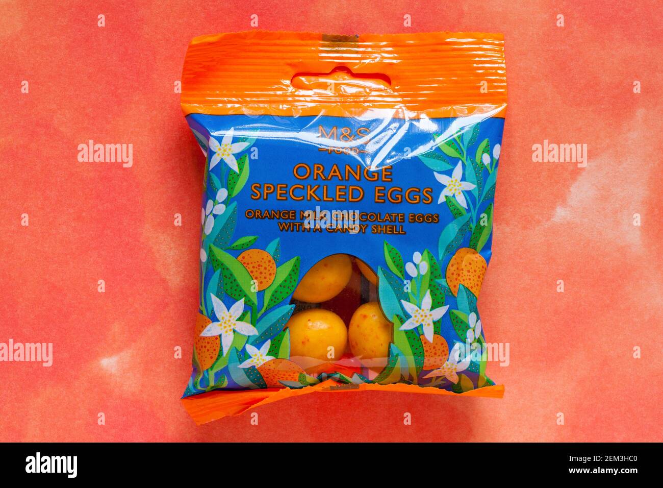 Paquet d'œufs orange M&S, œufs au chocolat au lait d'orange avec une carapace de bonbons, isolés sur fond orange à motifs - prêt pour Pâques Banque D'Images