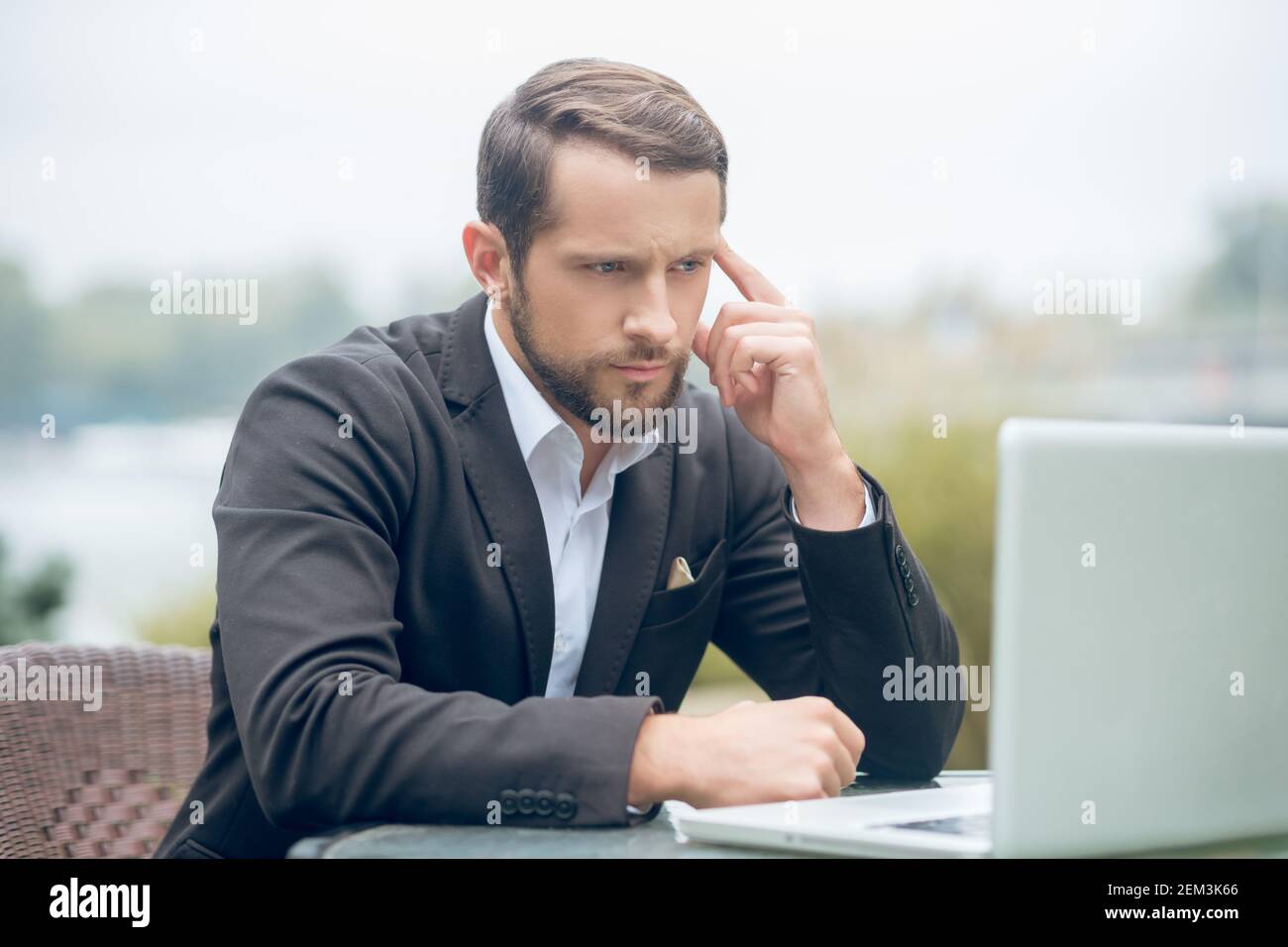 Un homme attrayant et réussi qui regarde sérieusement l'écran d'un ordinateur portable Banque D'Images