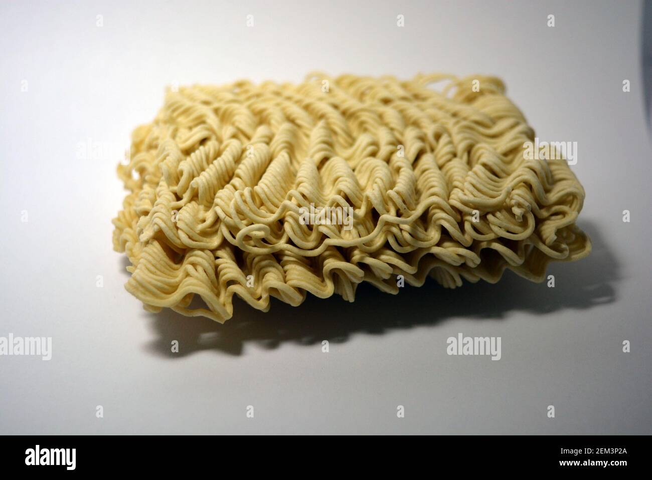 Vermicelles instantanées, briquette de vermicelles minces et longues sur fond blanc. Banque D'Images
