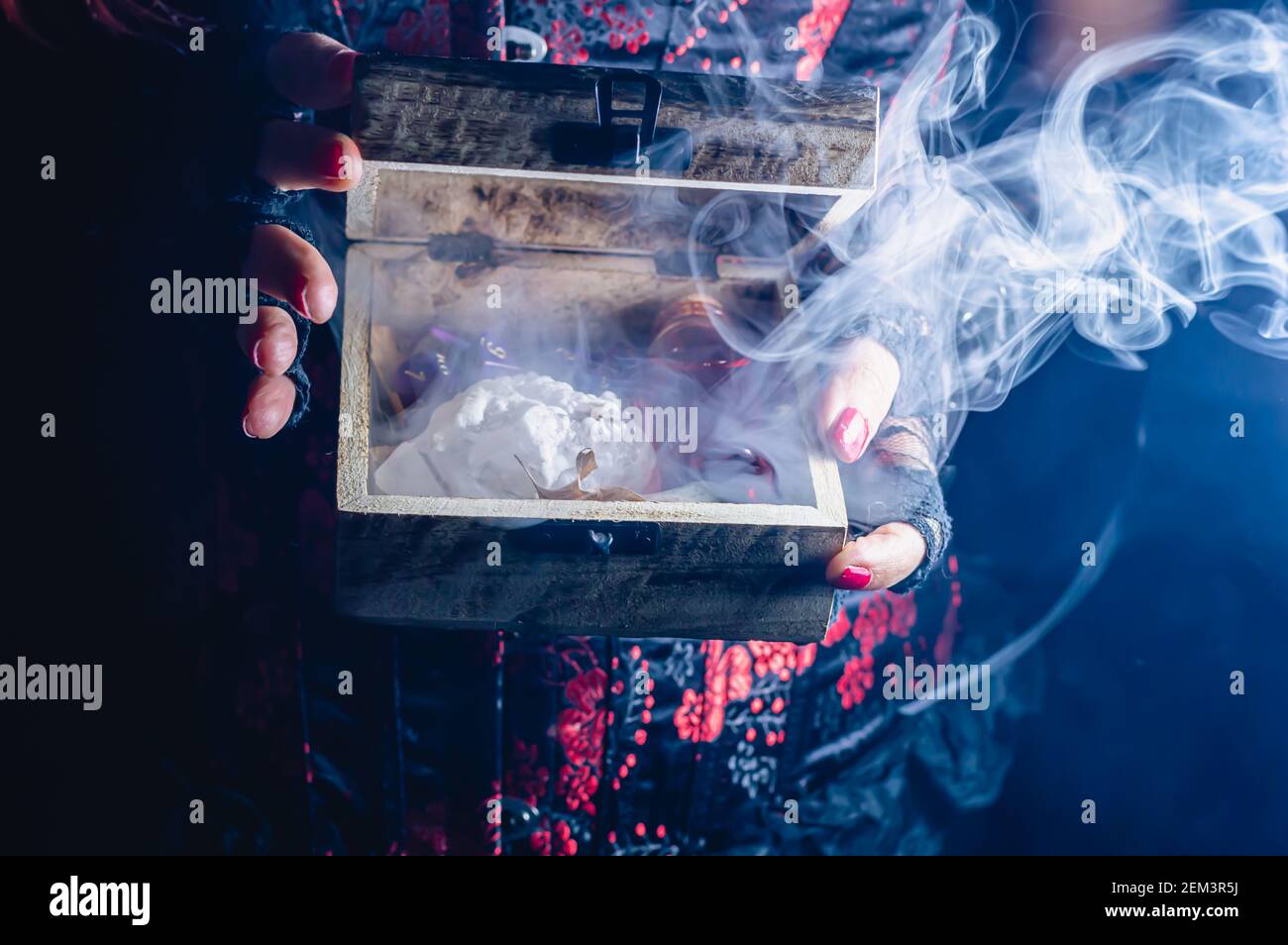 De la fumée s'échappe d'une boîte en bois que quelqu'un porte un corset  noir et rouge Photo Stock - Alamy