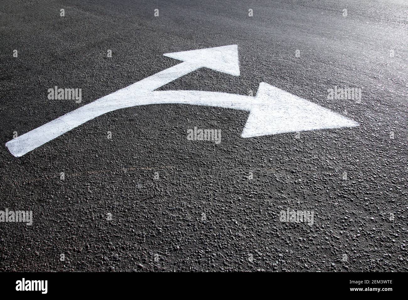 flèche directionnelle blanche dessinée sur le sol en asphalte - concept de trajectoires et de directions Banque D'Images