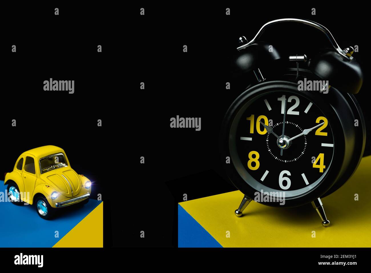 Voitures jouets et réveil sur fond sombre avec copie espace Banque D'Images