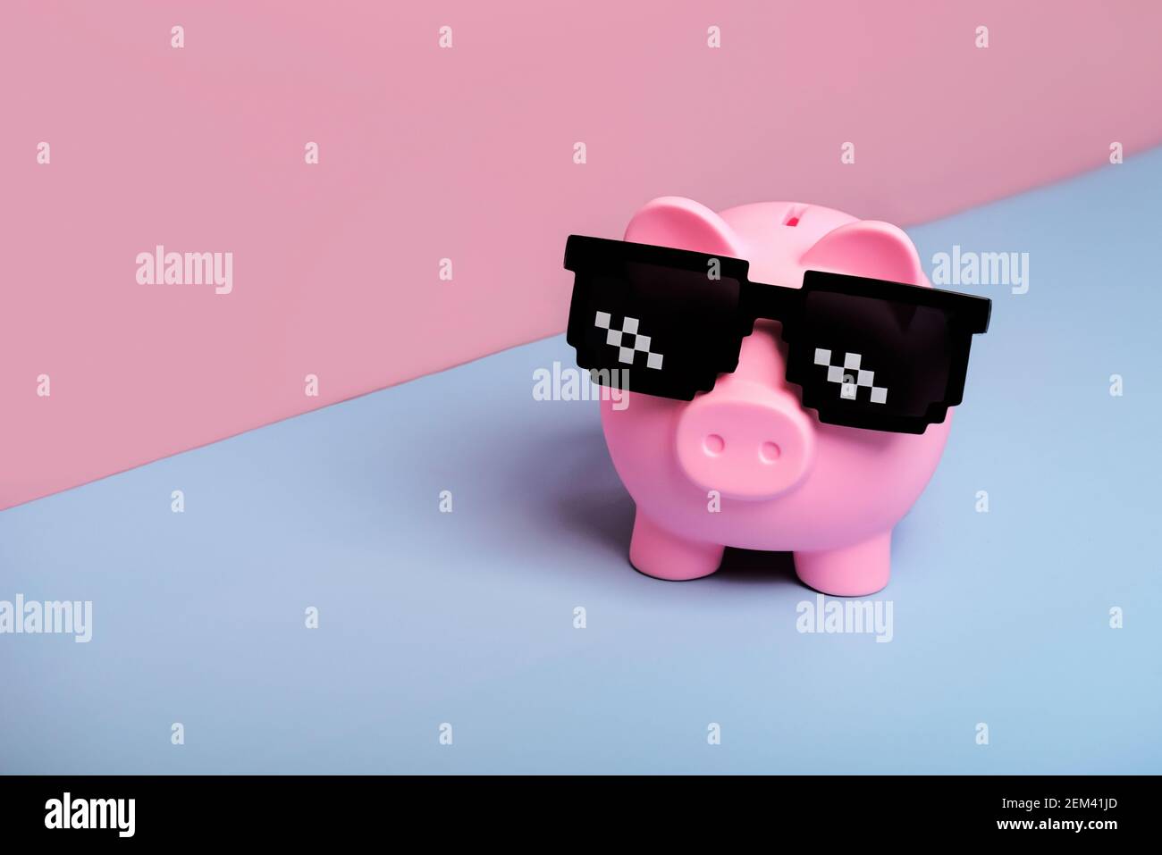 Banque d'argent de porc rose avec des lunettes de soleil noires sur rose et arrière-plan bleu Banque D'Images