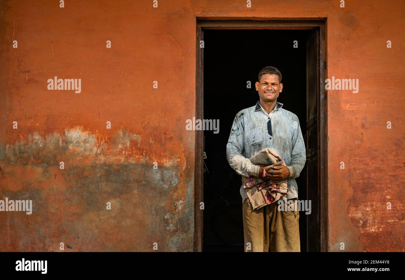 Portrait d'un homme souriant dans la porte employé comme travailleur manuel pour déplacer des sacs de ciment à la jonction de chemin de fer à Mathura, Uttar Pradesh, Inde. Banque D'Images