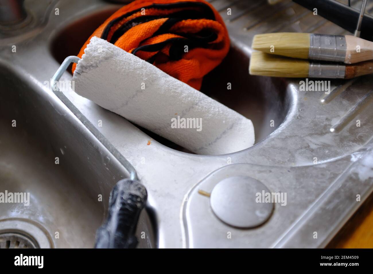 Brossettes de peinture et un rouleau de séchage dans un évier de cuisine. Banque D'Images