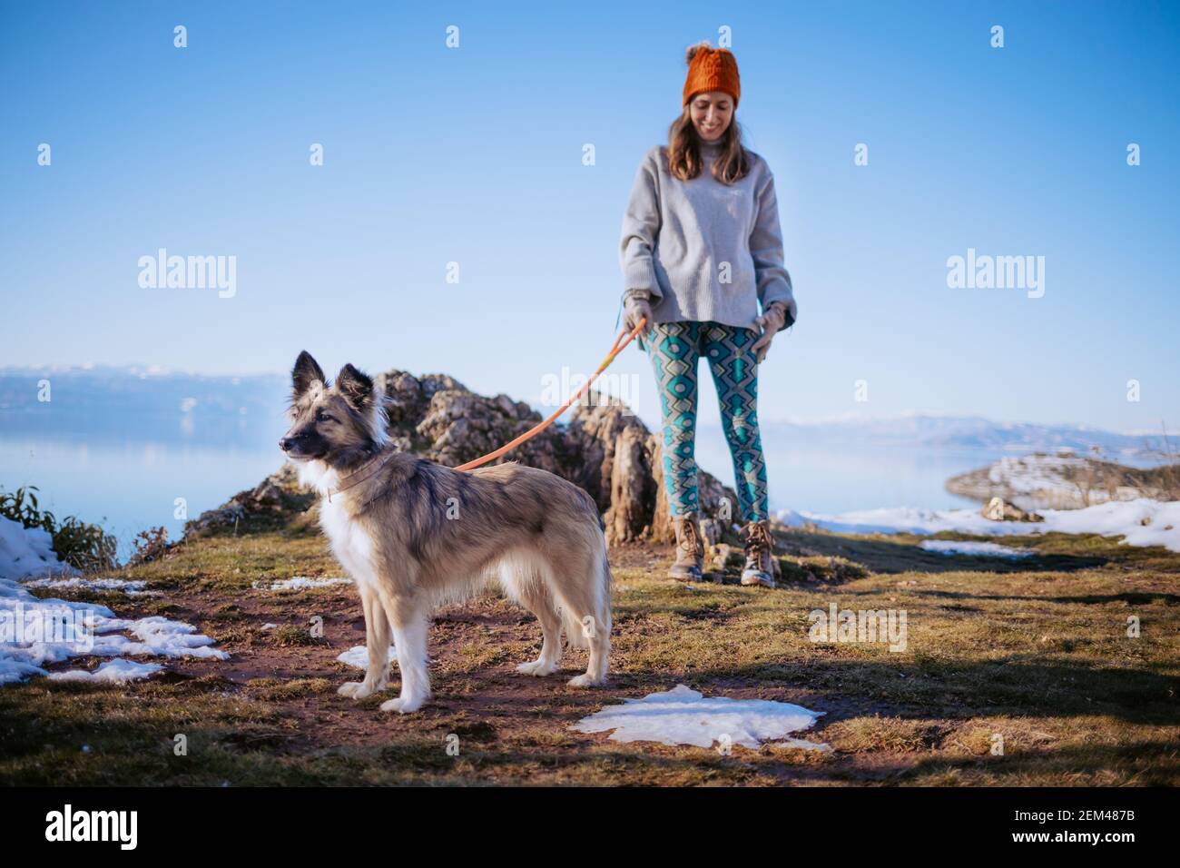 Femme marchant son chien sur une rive du lac en hiver Banque D'Images