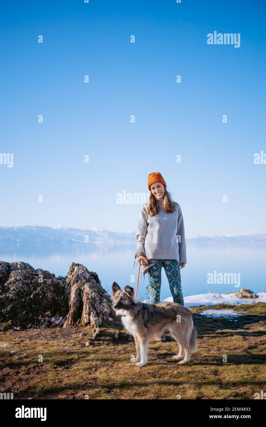 Femme marchant son chien sur une rive du lac en hiver Banque D'Images