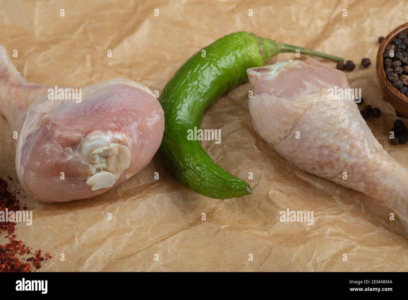 Cachez la photo de pilons de poulet crus avec du poivre papier alimentaire Banque D'Images