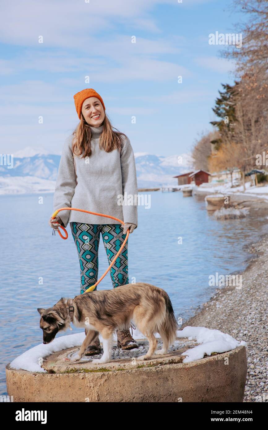 Femme marchant son chien sur une rive du lac en hiver Banque D'Images