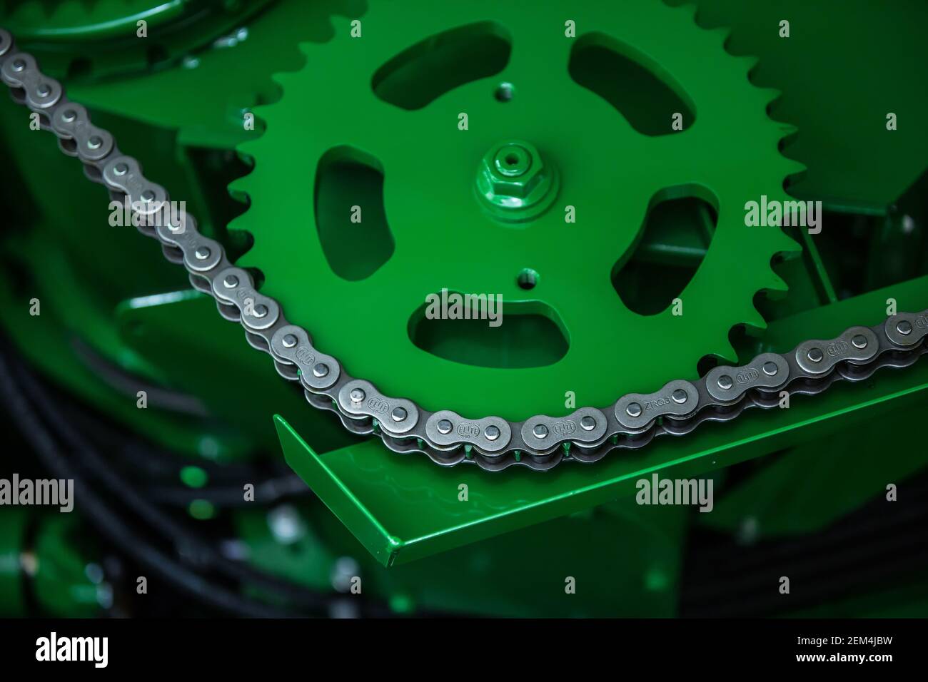 Une chaîne en acier sur une roue dentée verte Banque D'Images
