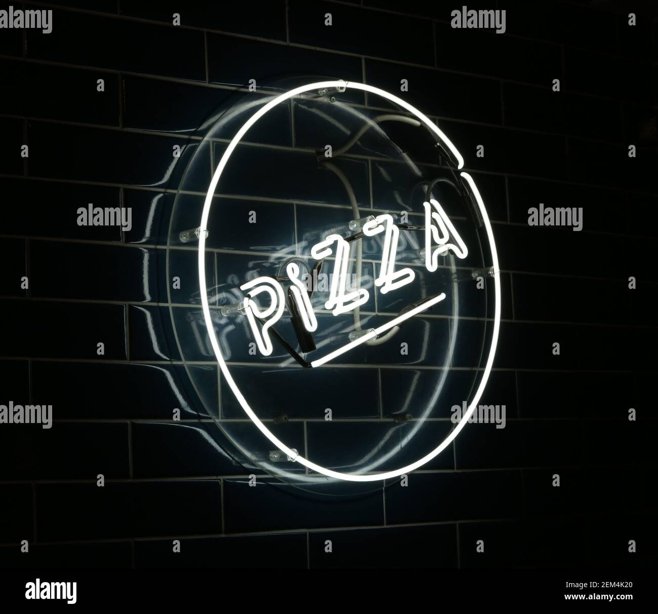 Une affiche lumineuse pour pizza au néon sur un mur carrelé Banque D'Images