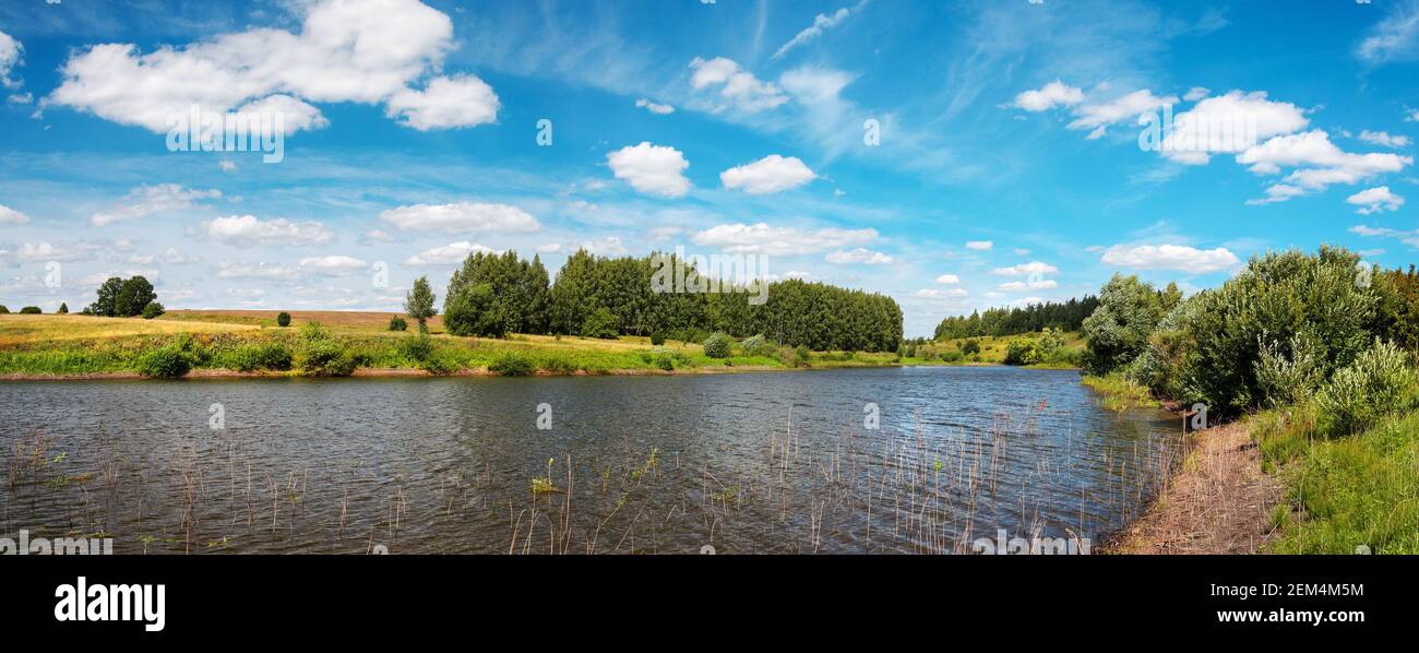 Paysage ensoleillé d'été avec collines vertes, rivière et beaux bois pendant la belle journée de juillet. Banque D'Images