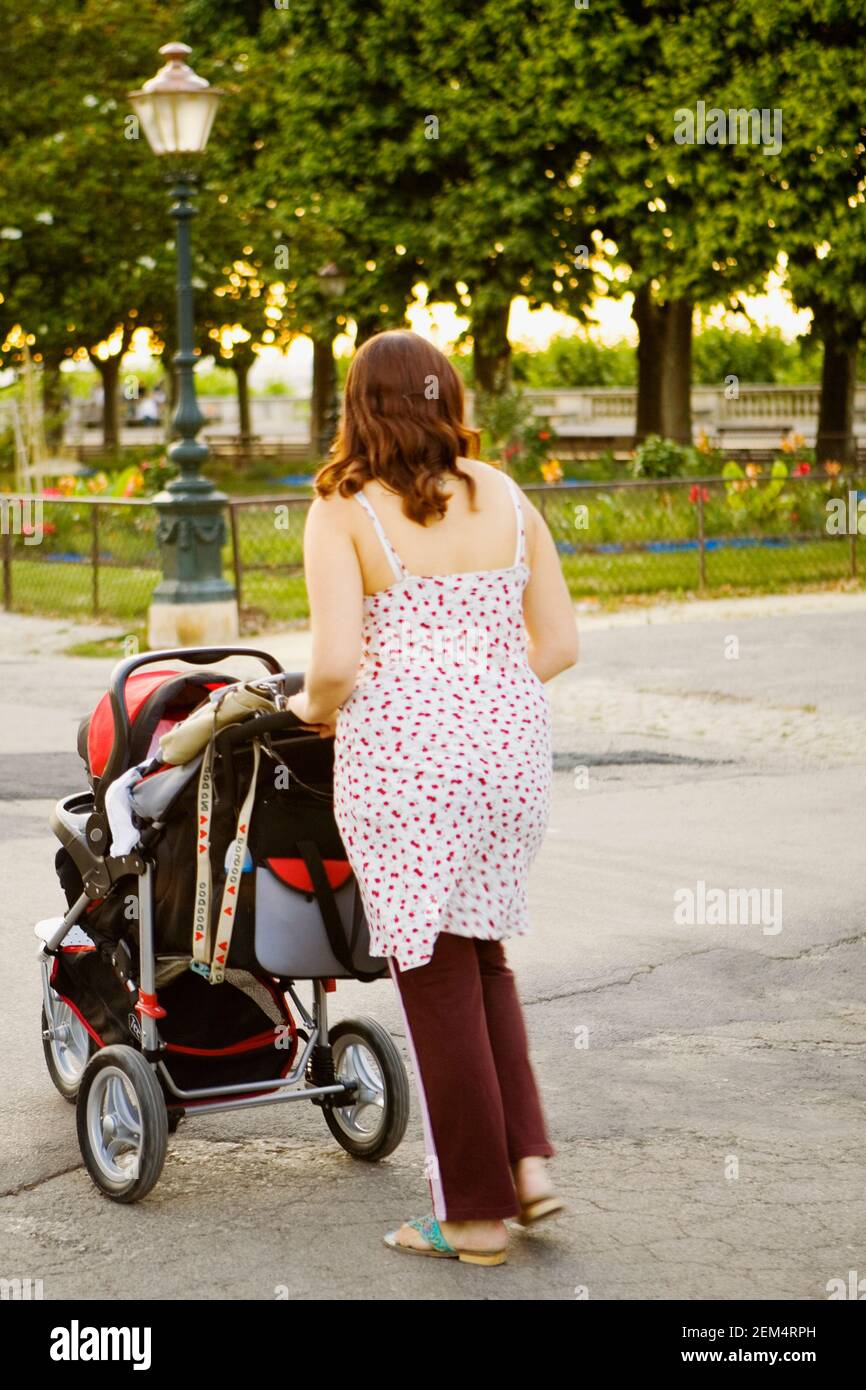Jeune femme poussant une poussette de bébé sur la route Banque D'Images