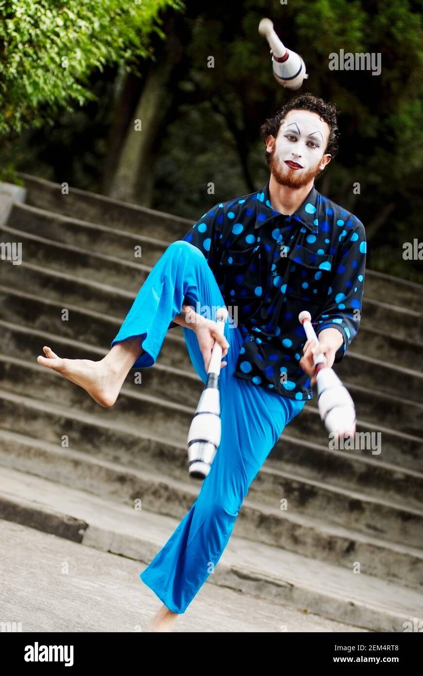 Portrait d'un homme adulte moyen avec un visage peint broches de jonglage Banque D'Images