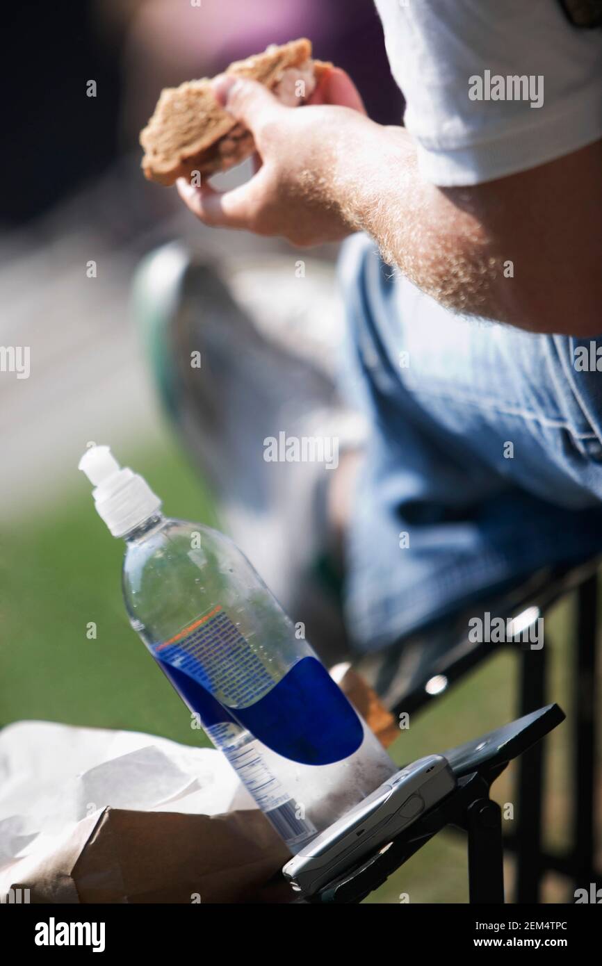 Gros plan d'un homme assis avec une bouteille de vodka et un téléphone portable sur la table Banque D'Images