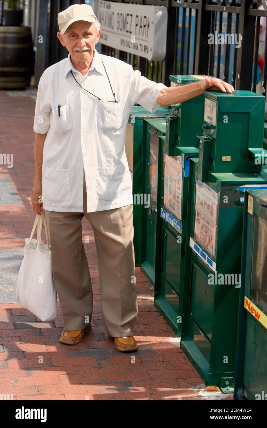 Portrait d'un homme âgé debout à côté des distributeurs automatiques de journaux Banque D'Images