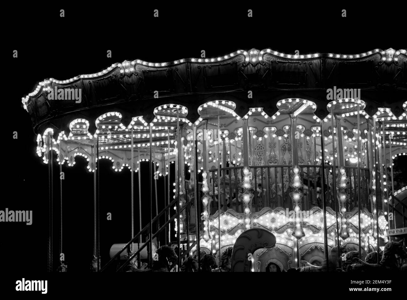 Des chevaux de manège dans un parc d'attractions éclairé la nuit Banque D'Images