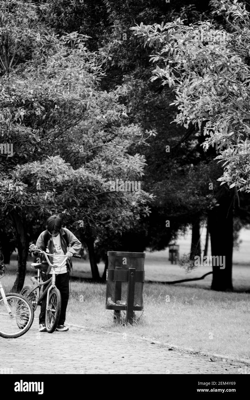 Garçon tenant un vélo près d'une poubelle Banque D'Images