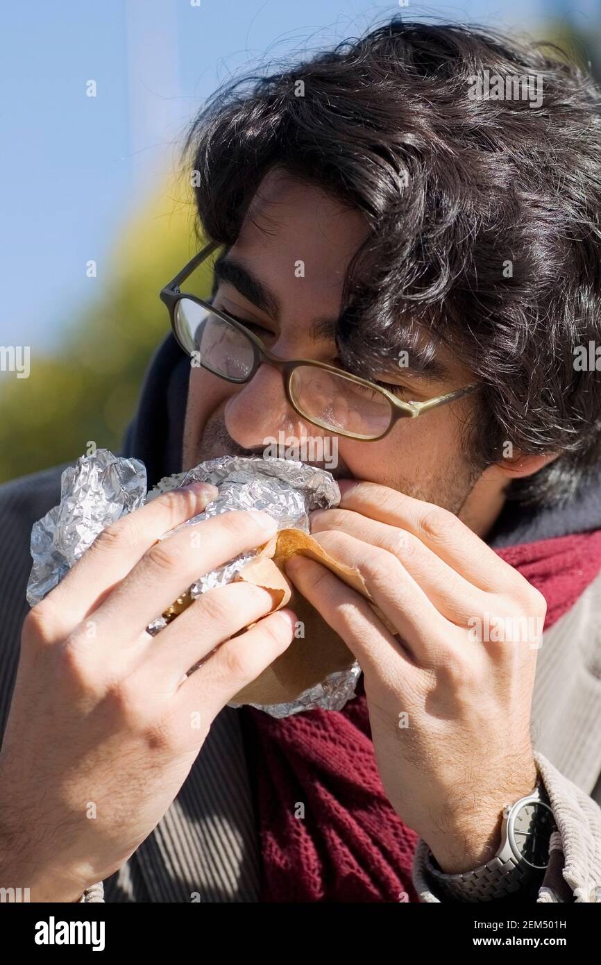 Gros plan sur un jeune homme mangeant un hamburger Banque D'Images