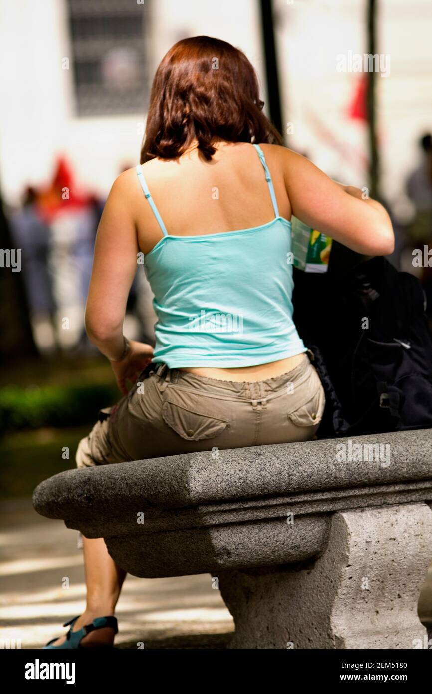 Vue arrière d'une jeune femme assise sur un banc, Madrid, Espagne Banque D'Images