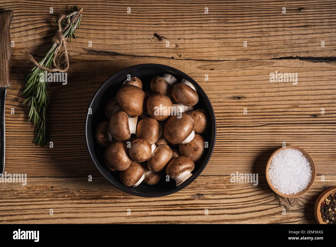 Bol de petits champignons bella et bouquet de romarin frais sur fond rustique en bois, vue d'en haut, nourriture à base de plantes Banque D'Images