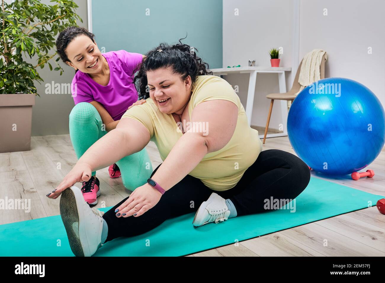Grosse femme portant des vêtements de sport s'entraînant et étirant ses jambes et son corps pendant l'aérobic avec un entraîneur personnel. entraînement sportif pour perdre du poids Banque D'Images